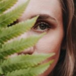 The girl hides her face behind a leaf