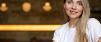 Close-up of a smiling blonde woman in a white t-shirt sitting in a cafe